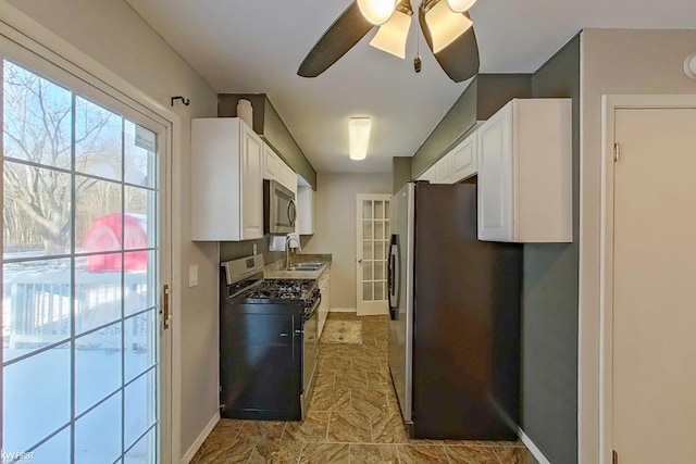 kitchen featuring appliances with stainless steel finishes, white cabinetry, ceiling fan, and sink