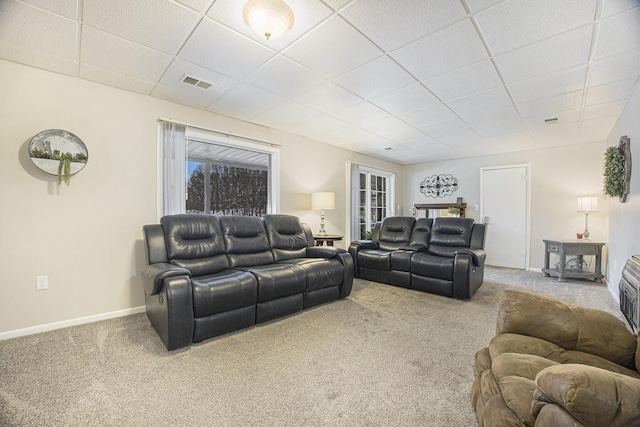 carpeted living room featuring a drop ceiling