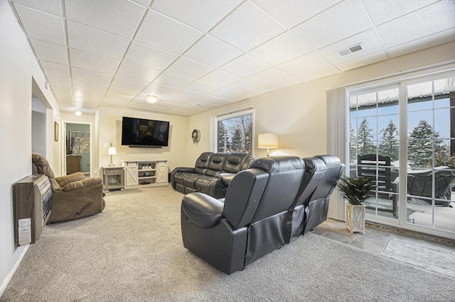 carpeted living room with a paneled ceiling and heating unit