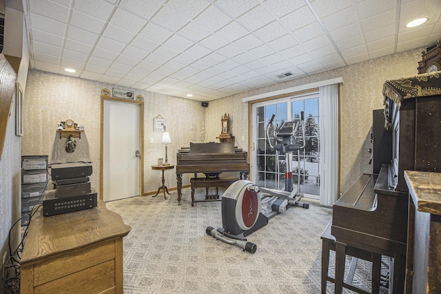 workout room with a drop ceiling and light colored carpet