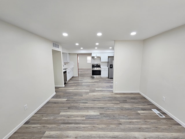 kitchen featuring backsplash, white cabinets, stainless steel appliances, and light wood-type flooring