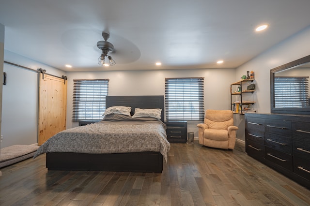 bedroom featuring a barn door, dark hardwood / wood-style floors, and ceiling fan