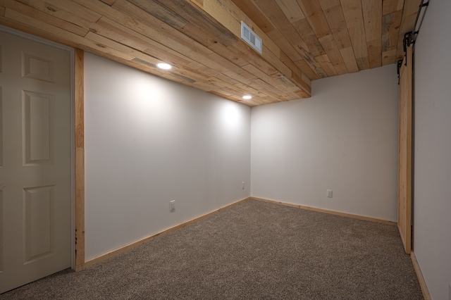 empty room featuring carpet flooring, a barn door, and wooden ceiling