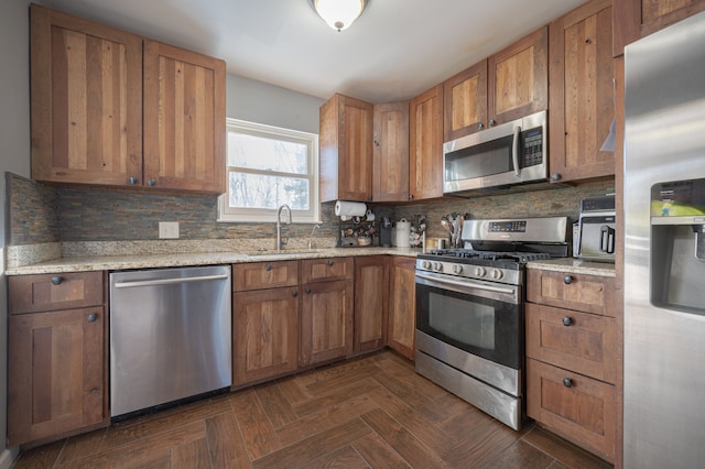 kitchen featuring light stone countertops, appliances with stainless steel finishes, backsplash, dark parquet flooring, and sink