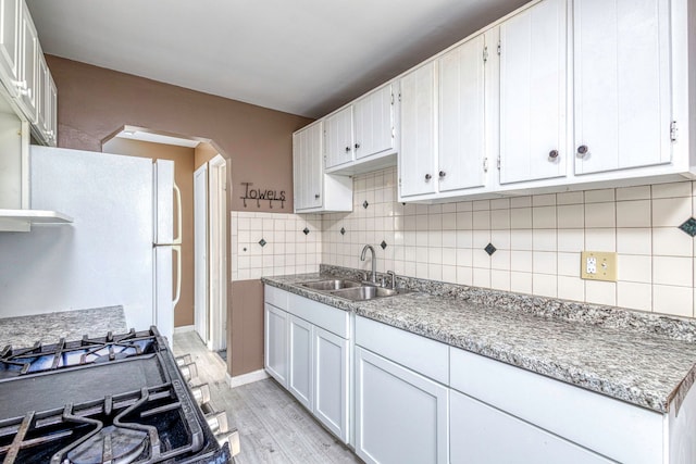 kitchen with light wood-type flooring, white cabinetry, and sink