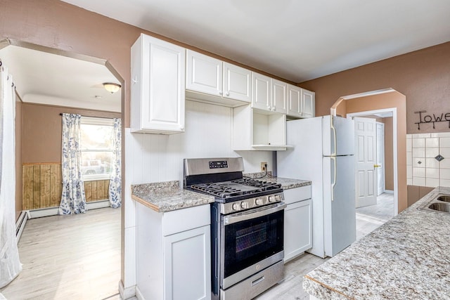 kitchen featuring light hardwood / wood-style floors, white cabinetry, white refrigerator, and gas range