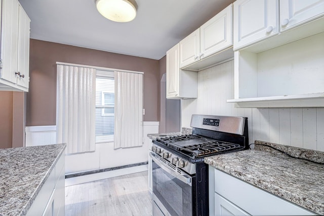 kitchen with white cabinets, light wood-type flooring, light stone counters, and stainless steel gas range oven