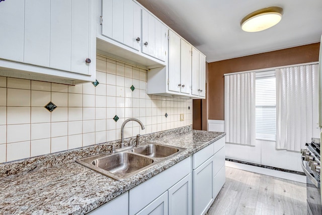 kitchen featuring white cabinets, sink, light wood-type flooring, stainless steel range, and light stone counters