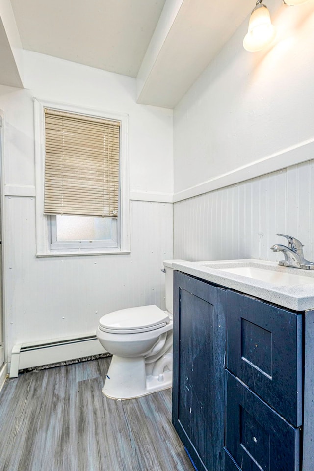 bathroom featuring hardwood / wood-style floors, vanity, wood walls, toilet, and a baseboard radiator