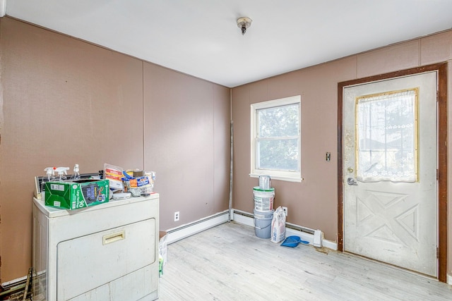 clothes washing area featuring washer / dryer, light hardwood / wood-style flooring, and a baseboard heating unit