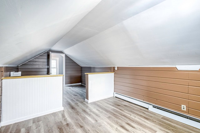 bonus room featuring wood walls, vaulted ceiling, baseboard heating, and light hardwood / wood-style flooring