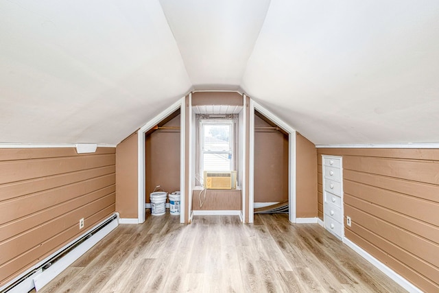 additional living space featuring wood walls, cooling unit, vaulted ceiling, light wood-type flooring, and baseboard heating