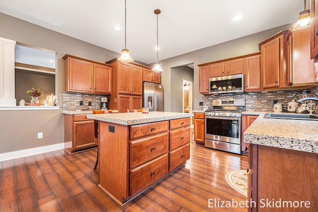 kitchen with stainless steel appliances, sink, decorative light fixtures, dark hardwood / wood-style floors, and a kitchen island