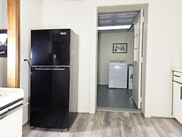 kitchen featuring black fridge, white cabinetry, and light wood-type flooring