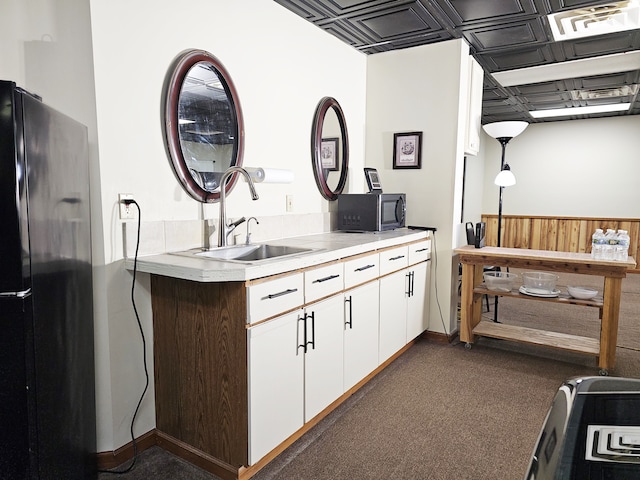 kitchen with white cabinetry, sink, black appliances, and dark colored carpet