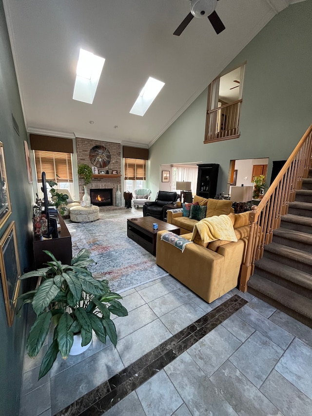 living room with a fireplace, ceiling fan, crown molding, and high vaulted ceiling