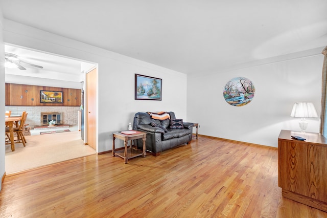 sitting room with a fireplace, light hardwood / wood-style flooring, and ceiling fan