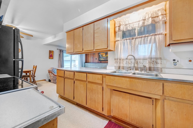 kitchen featuring backsplash, black refrigerator, sink, and light brown cabinetry