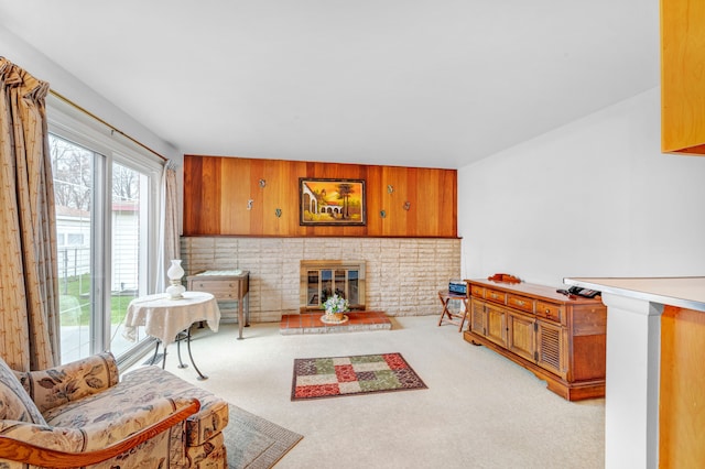 sitting room with light carpet, wooden walls, and a brick fireplace