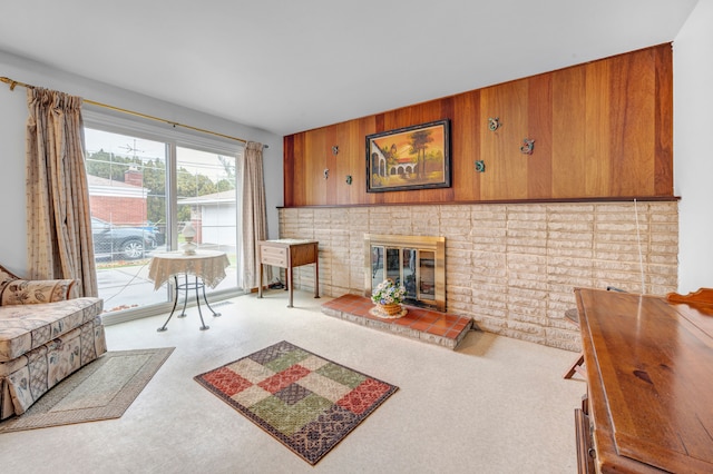 living room featuring a fireplace, light carpet, and wooden walls