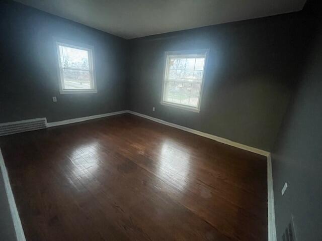 unfurnished room with dark wood-type flooring