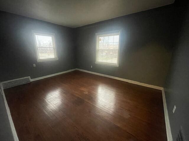 spare room with a healthy amount of sunlight and dark wood-type flooring