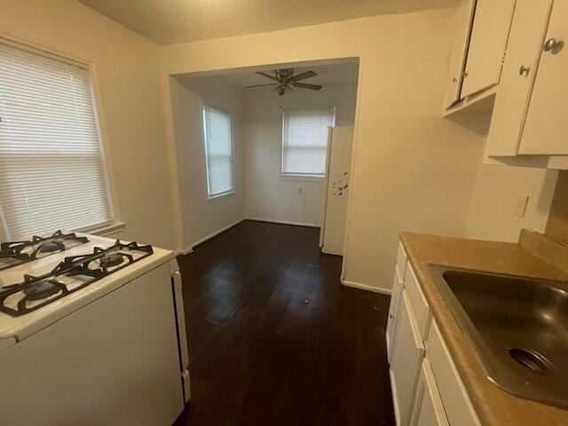 kitchen with dark hardwood / wood-style floors, white gas stove, white cabinetry, ceiling fan, and sink