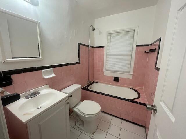 full bathroom featuring tile patterned flooring, toilet, vanity, tile walls, and tiled shower / bath