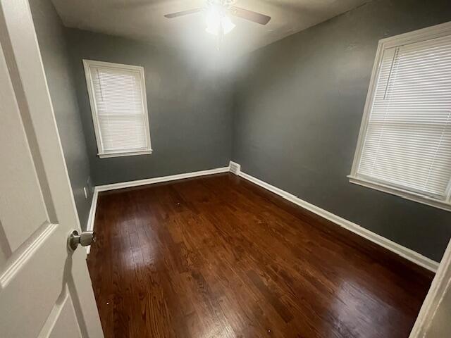 unfurnished room featuring dark wood-type flooring and ceiling fan