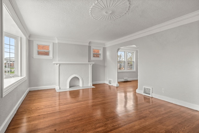 unfurnished living room featuring crown molding, plenty of natural light, and hardwood / wood-style floors