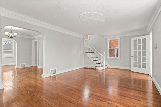 unfurnished living room featuring plenty of natural light, wood-type flooring, a textured ceiling, and ornamental molding