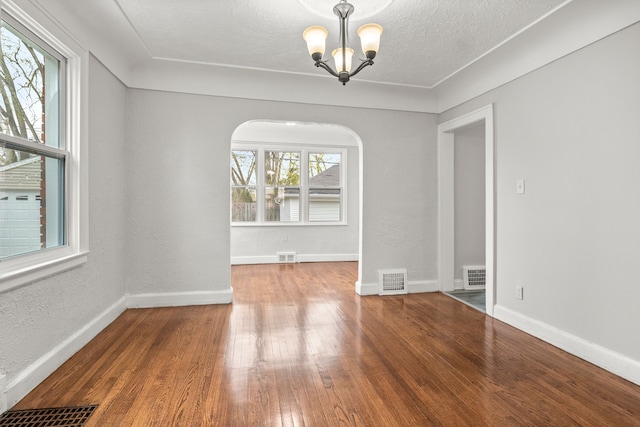 unfurnished dining area featuring hardwood / wood-style floors, a textured ceiling, and an inviting chandelier