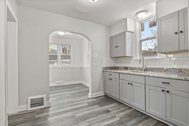 kitchen featuring light wood-type flooring, backsplash, gray cabinets, and sink