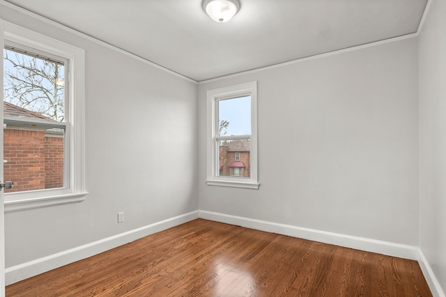 empty room with crown molding, plenty of natural light, and hardwood / wood-style flooring