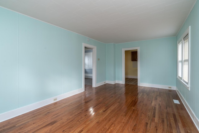 unfurnished room featuring visible vents, baseboards, and wood finished floors