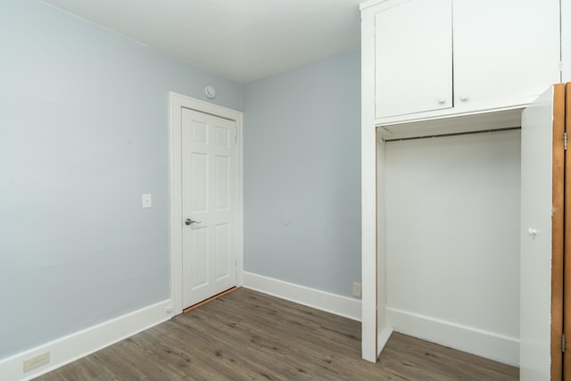 unfurnished bedroom featuring baseboards and dark wood-style flooring