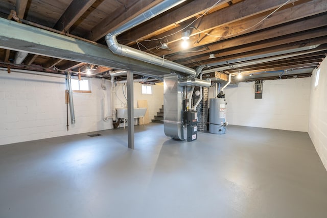 basement featuring heating unit, water heater, and a sink