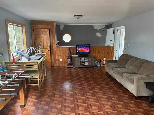 living room with dark parquet floors and wood walls