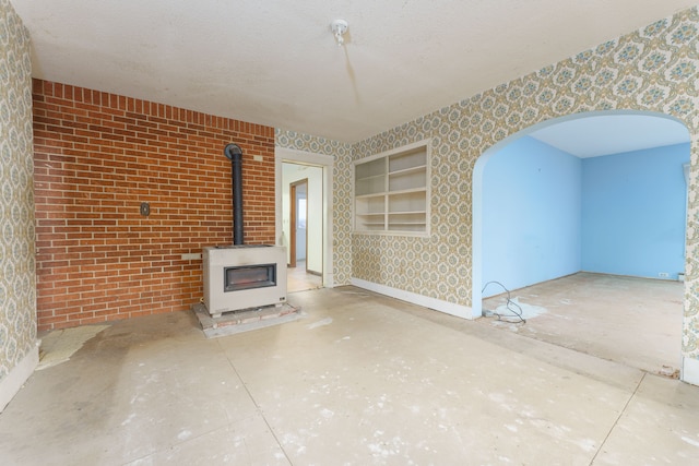 unfurnished living room featuring a wood stove and a textured ceiling