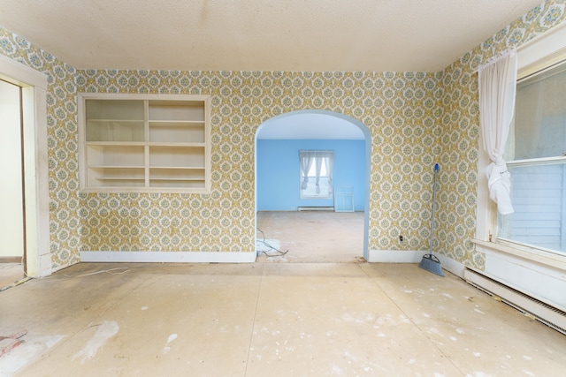 empty room featuring a textured ceiling and a baseboard heating unit