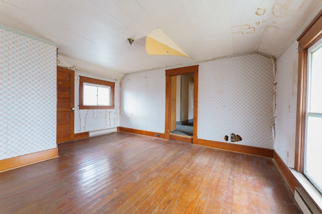 spare room featuring a healthy amount of sunlight, hardwood / wood-style flooring, baseboard heating, and lofted ceiling