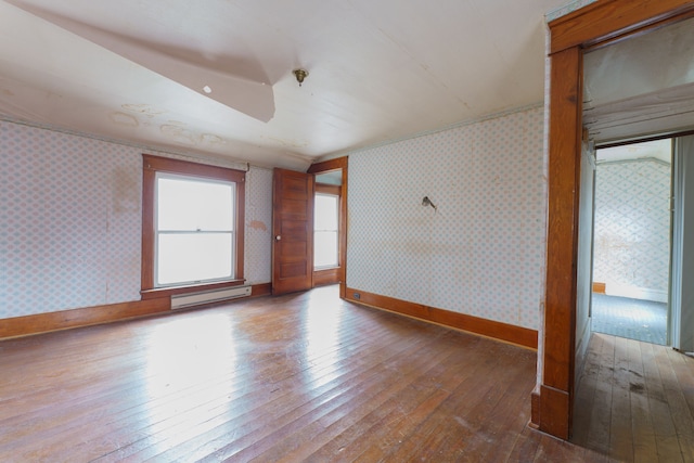 empty room featuring hardwood / wood-style floors and a baseboard radiator