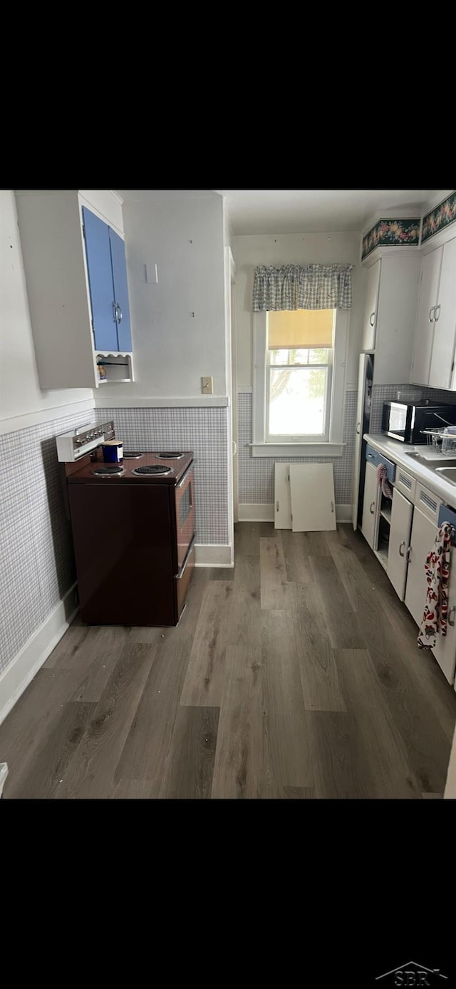 kitchen featuring electric range, dark hardwood / wood-style flooring, and white cabinets