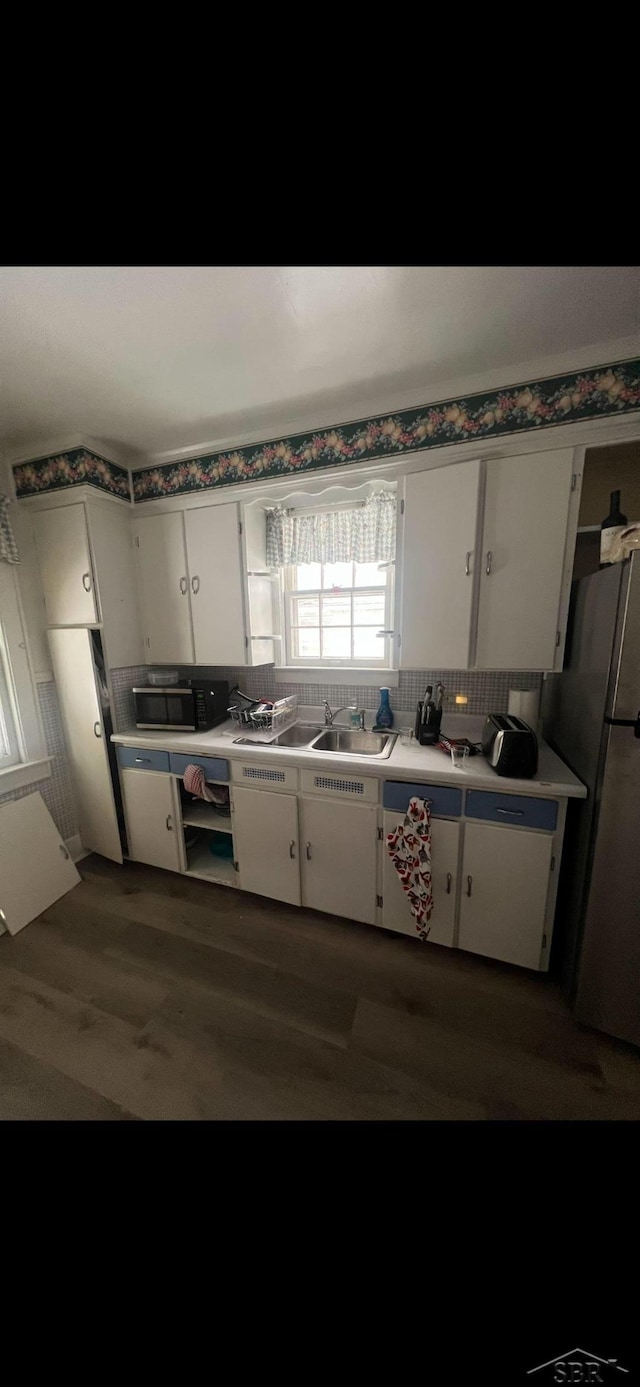 kitchen with dark hardwood / wood-style flooring, white cabinetry, backsplash, and stainless steel refrigerator