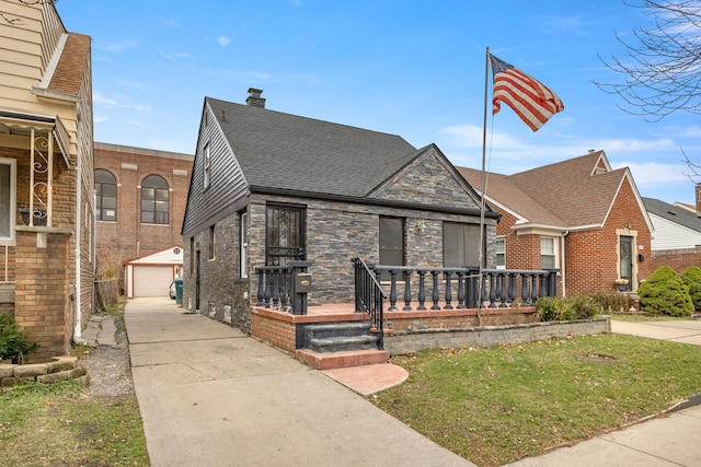 view of front facade featuring an outbuilding, a garage, a front lawn, and covered porch