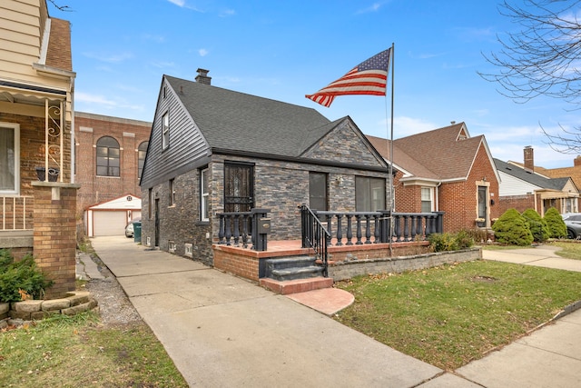 view of front of home featuring a porch, a garage, an outbuilding, and a front yard