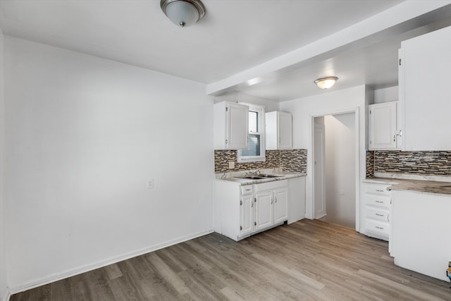 kitchen with decorative backsplash, white cabinetry, sink, and light hardwood / wood-style flooring