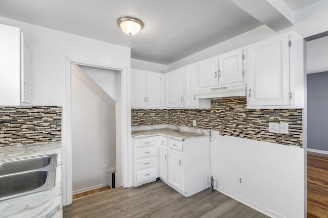 kitchen featuring light stone countertops, white cabinetry, light hardwood / wood-style floors, and custom range hood