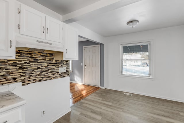 kitchen featuring white cabinets, light wood-type flooring, and backsplash