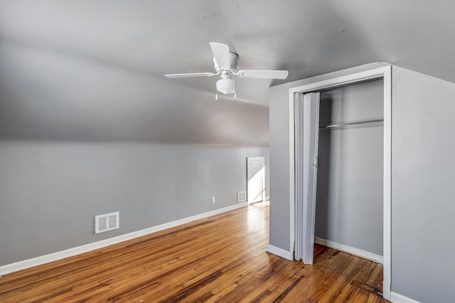 unfurnished bedroom with ceiling fan, a closet, wood-type flooring, and vaulted ceiling